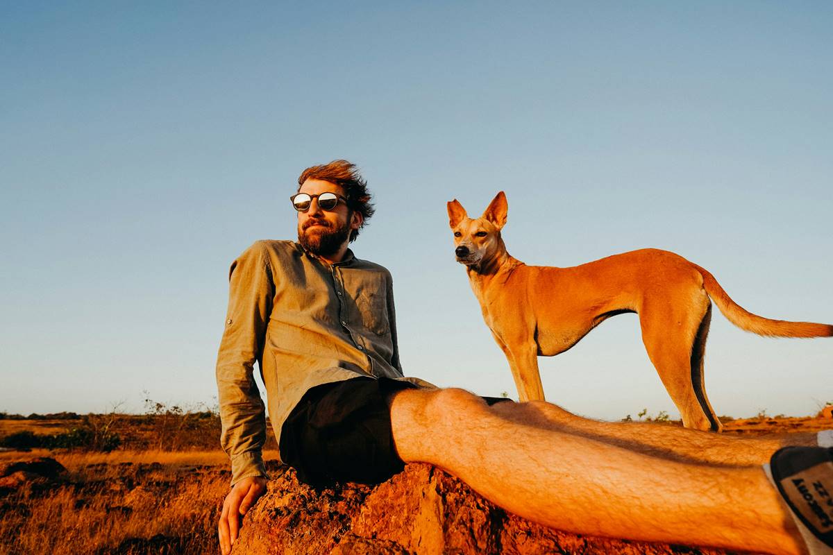 Basenji z właścicielem leży, zachód słońca.